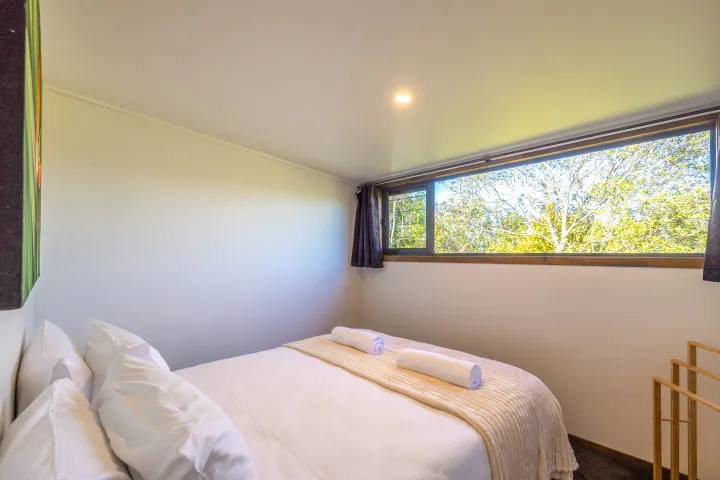 Harvest Cottage Waiheke Island Bedroom 2 with garden views and tasteful artwork.