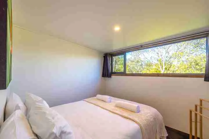 Harvest Cottage Waiheke Island Bedroom 2 with garden views and tasteful artwork.