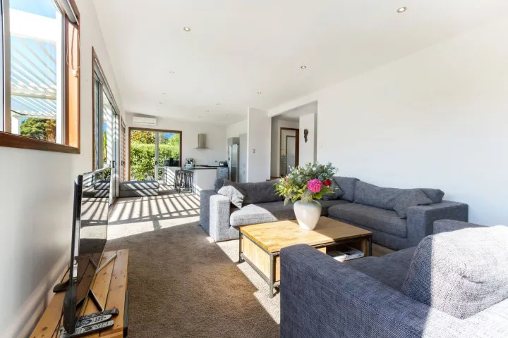 Stay in open plan comfort at Karaka with large couches, TV, coffee table and deck access
